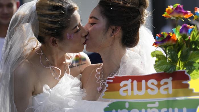 Women kiss while holding a poster to support marriage equality, during a Pride Parade in Bangkok, Thailand, on June 4, 2023.