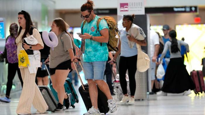 Travelers walk through Miami International Airport, Wednesday, July 3, 2024, in Miami