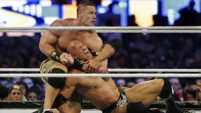 Wrestler John Cena, top, chokes Dwayne Douglas Johnson, known as The Rock, as they wrestle, April 7, 2013, in East Rutherford, N.J., during Wrestlemania.
