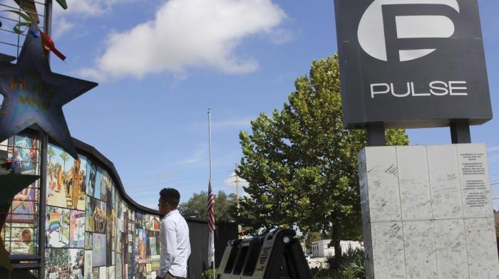 Brandon Wolf, a survivor of the Pulse nightclub shooting and activist, looks at the photos that are a part of the Pulse memorial in Orlando, Fla., on Sept. 9, 2022.