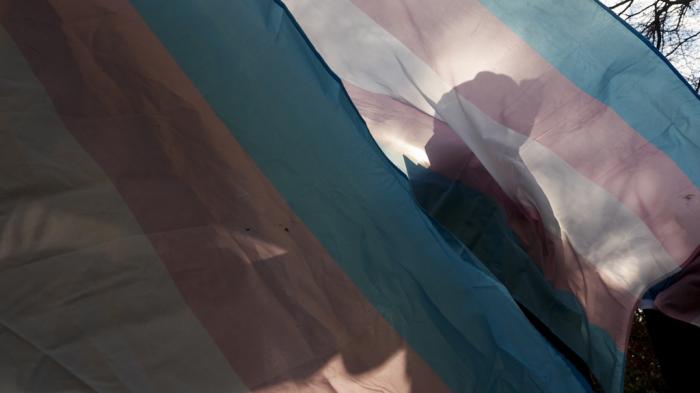 A protester is silhouetted against a trans pride flag during a pro-transgender rights protest outside of Seattle Children's Hospital, in Seattle, Feb. 9, 2025. 