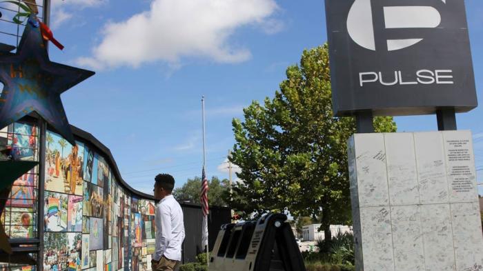 Brandon Wolf, a survivor of the Pulse nightclub shooting and activist, looks at the photos that are a part of the Pulse memorial in Orlando, Fla., on Sept. 9, 2022