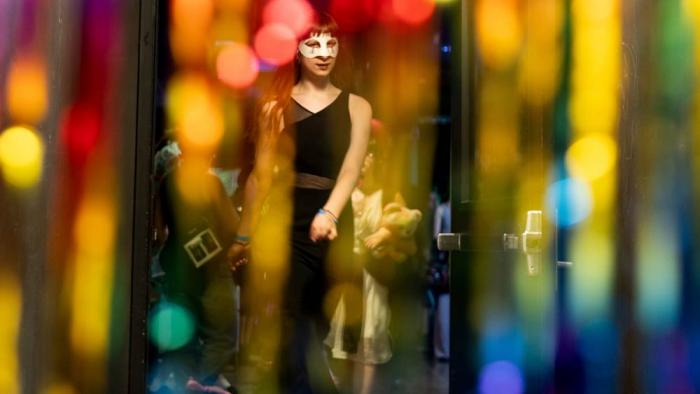 Melody Jenkins is seen through rainbow streamers during a "Pink Pony Prom" organized by the Sexual & Gender Minority Youth Resource Center, part of New Avenues for Youth, a nonprofit dedicated to ending youth homelessness, on Friday, May 30, 2025, in Portland, Ore.