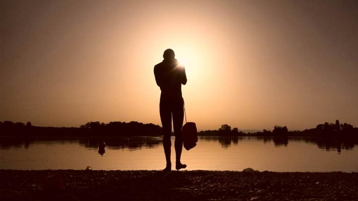A man prepares to enter the water as the sun rises above the Miribel lake, outside Lyon, France, June 18, 2022