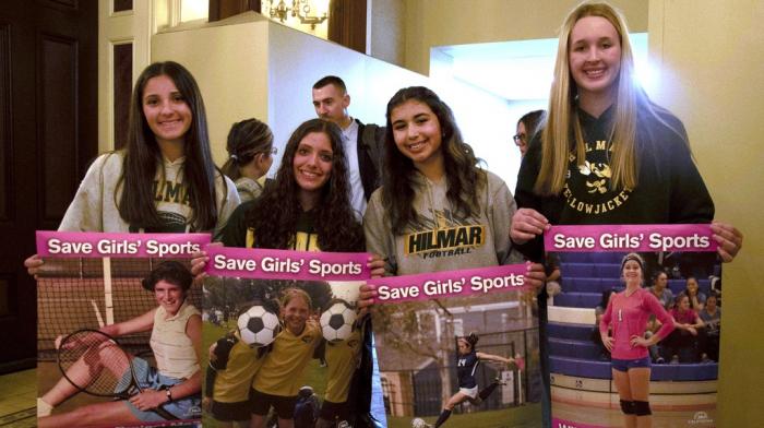 Student athletes hold signs during a hearing to consider bills to pass rules banning transgender student-athletes, April 1, 2025, in Sacramento, Calif.
