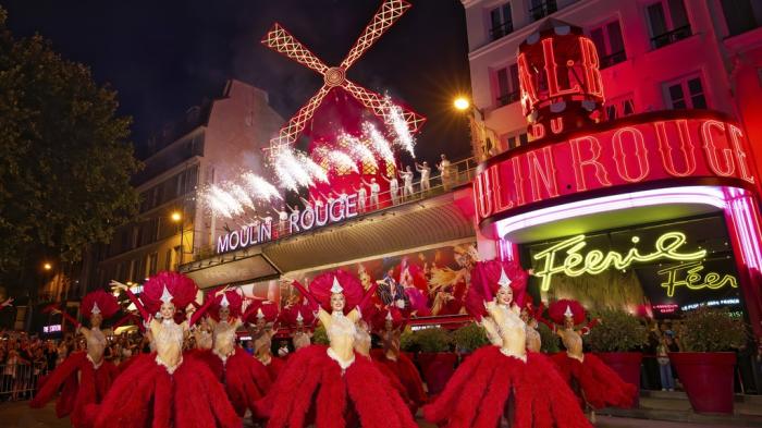 Dancers perform in front of the Moulin Rouge cabaret during the inauguration of the theatre's windmill in Paris, Friday, July 5, 2024.
